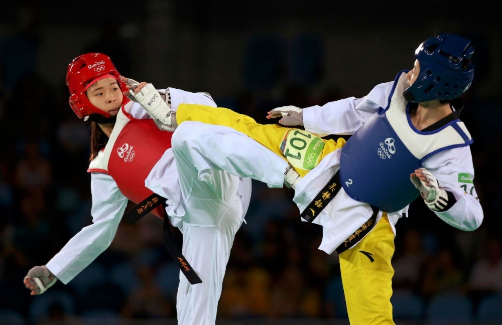 跆拳道小將黃懷萱（左）17日在女子49公斤級比賽不敵中國名將吳靜鈺（右），以1比10落敗，最後慘遭淘汰。（湯森路透）
