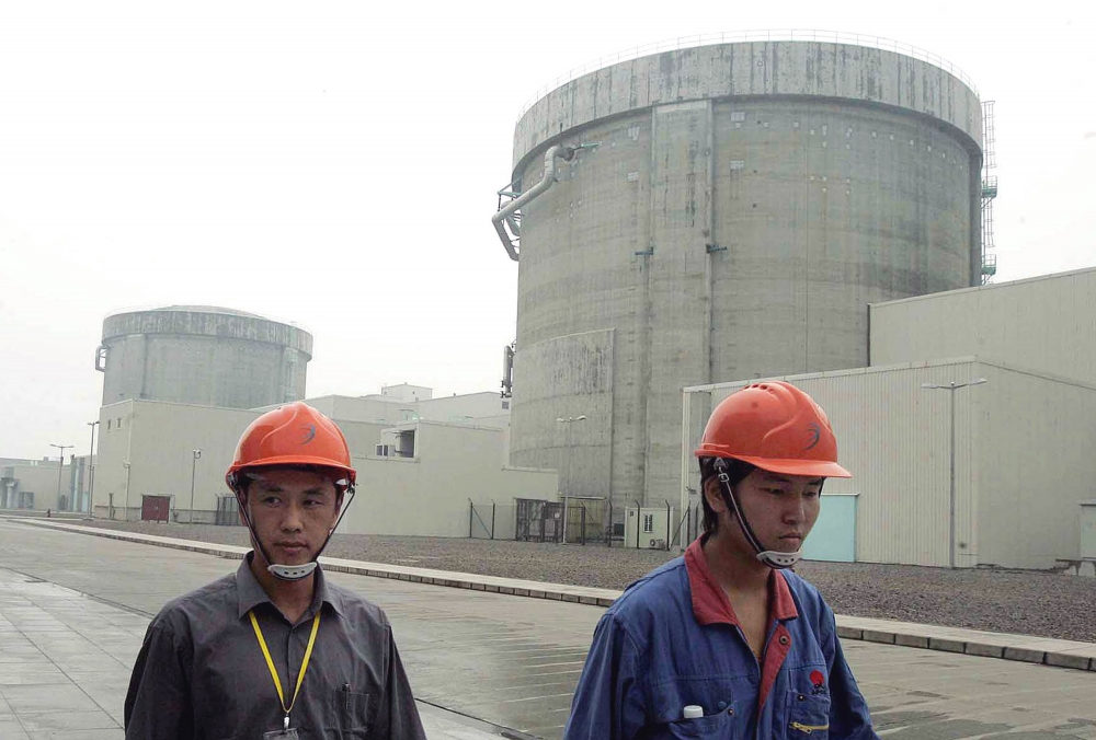 圖中背景為中國自行設計建造的第一座核能發電廠，秦山發電場（美聯社）
