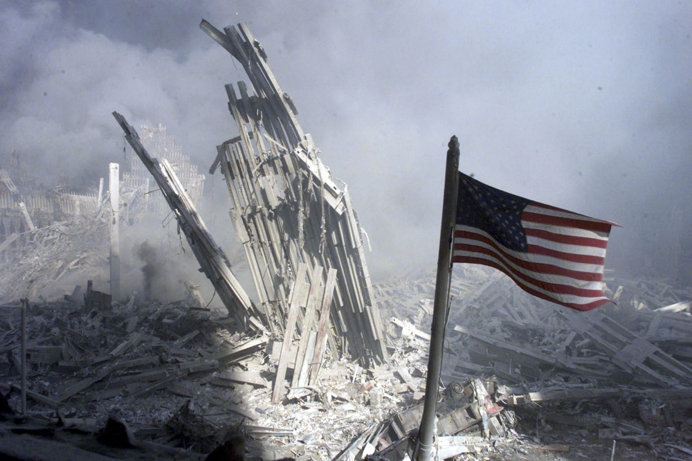 美國世貿雙子星大樓遺骸與美國國旗。（湯森路透）