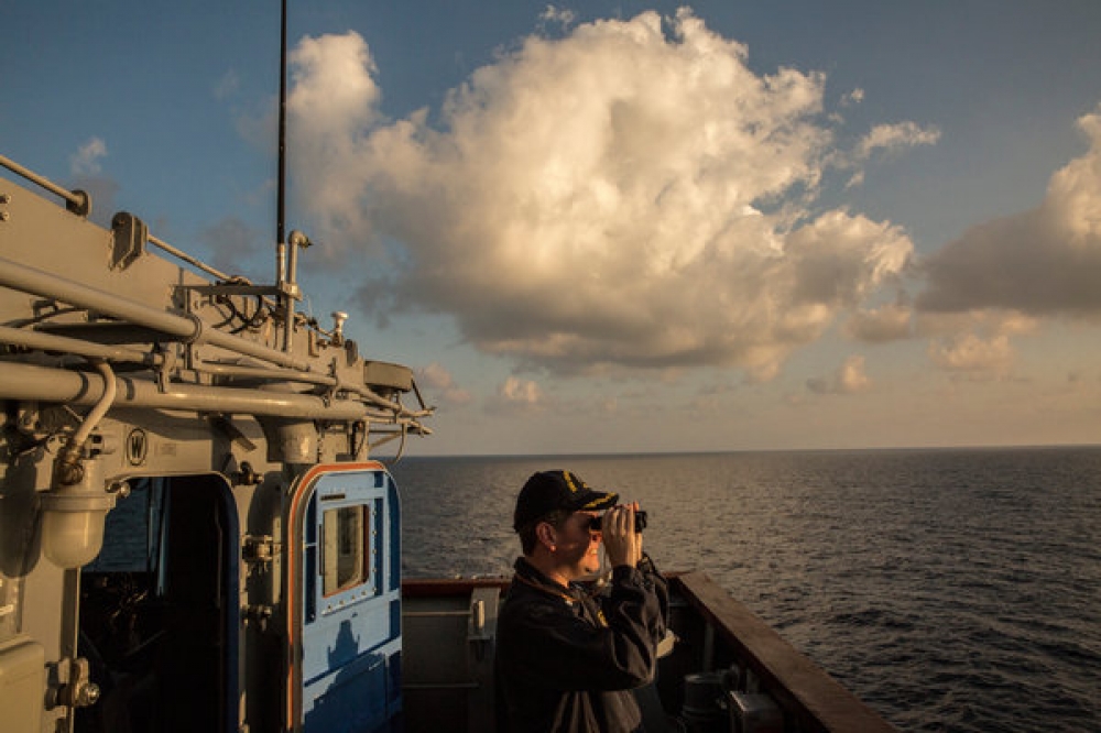 美軍切斯勞維爾號飛彈巡洋艦3月在南海巡航期間，海軍中尉斯密特持望遠鏡觀察一艘中國護衛艦。　（紐約時報） 