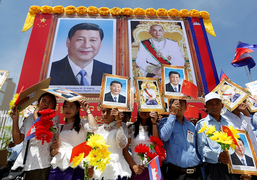 13日，金邊的民眾們站在習近平（左）與柬埔寨國王西哈莫尼（右）的畫像前熱烈歡迎習近平到訪。（湯森路透）