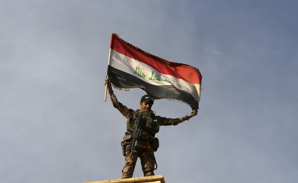 收復摩蘇爾郊外的巴特拉（Bartella）鎮後，一名伊拉克士兵高舉國旗。（美聯社）