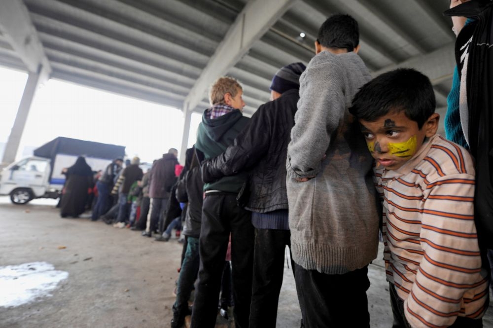 1名敘利亞男孩排隊等著領取救濟物資。（湯森路透）