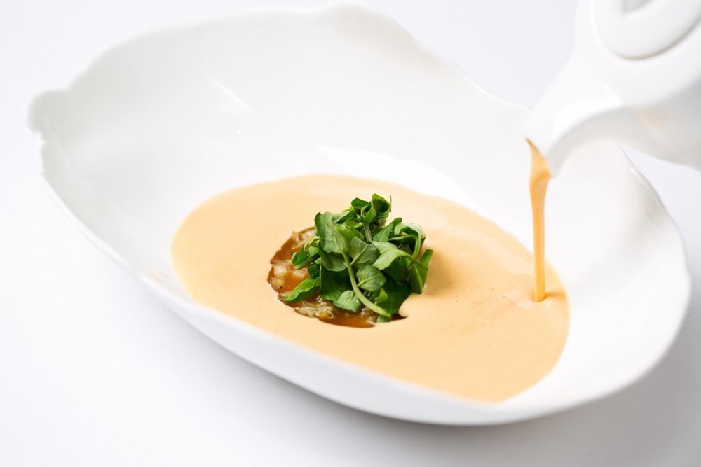 「黃道蟹濃湯」上桌前將精華濃湯倒入湯碗中，讓湯汁的熱氣化開蟹肉凍（圖片：國賓飯店）