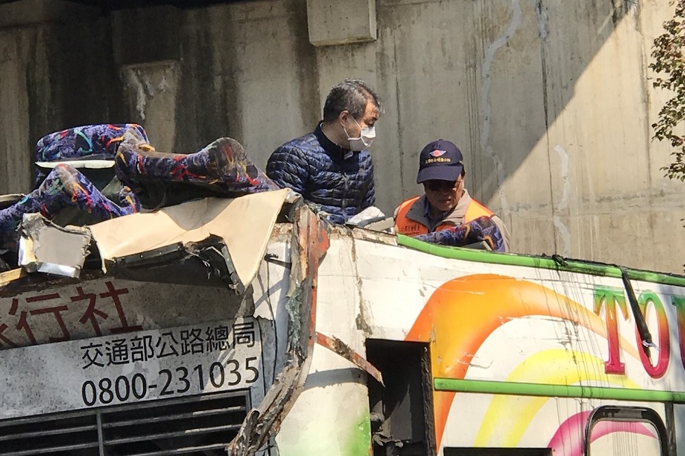 士檢主任檢察官吳怡明（左），在像開罐頭一樣被掀開的遊覽車上，指揮警方鑑識人員採證。（攝影：盧禮賓）