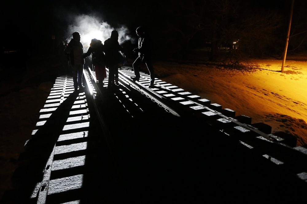 8名索馬利亞移民26日凌晨時分，由美國沿著鐵道走入加拿大境內。（美聯社）