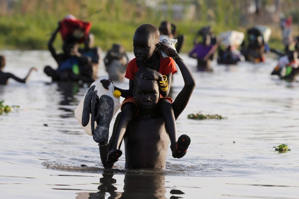飽受飢荒之苦的南蘇丹兒童涉溪領取糧食補給。　（湯森路透）