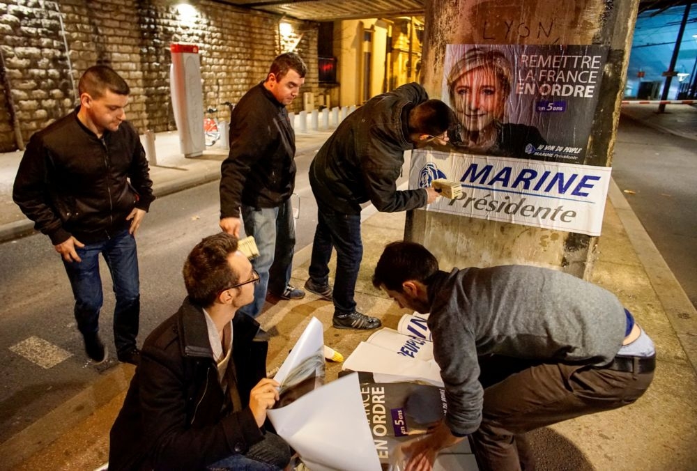 法國民族陣線年輕支持者在里昂街頭張貼競選宣傳單。（湯森路透）