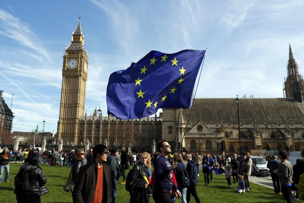參與遊行的民眾於倫敦國會廣場手持歐盟旗幟。（湯森路透）