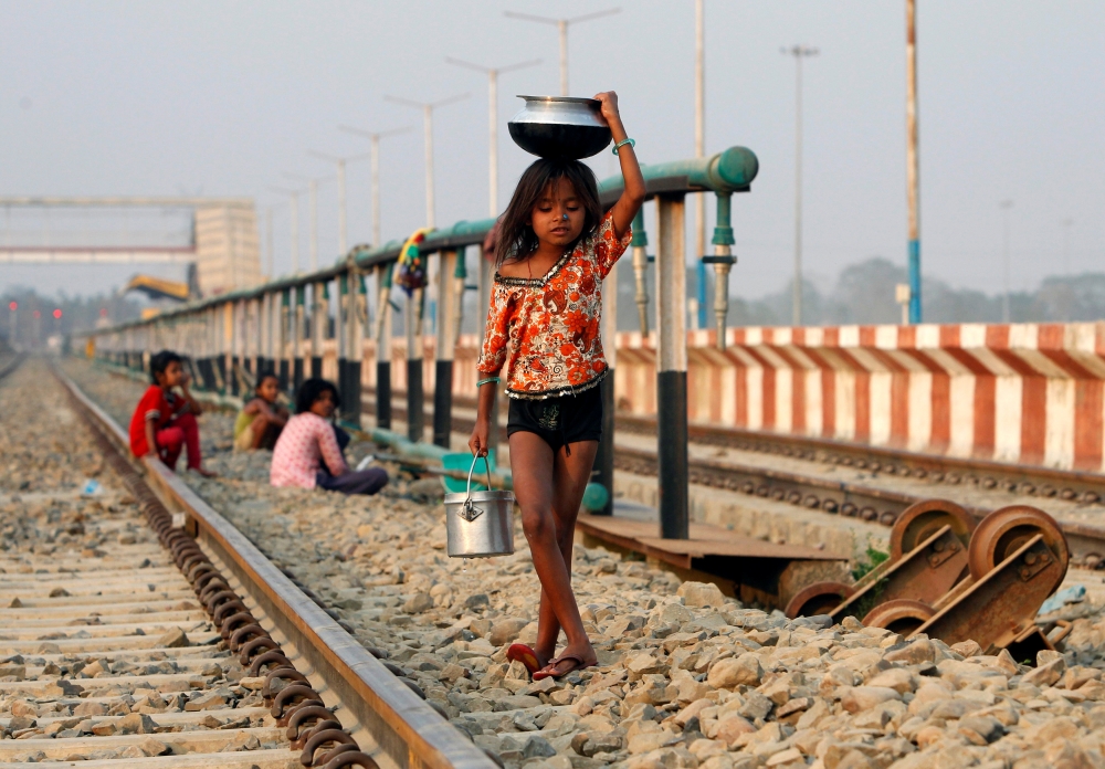 一位印度女孩從火車站的水源運輸管取水。（湯森路透）