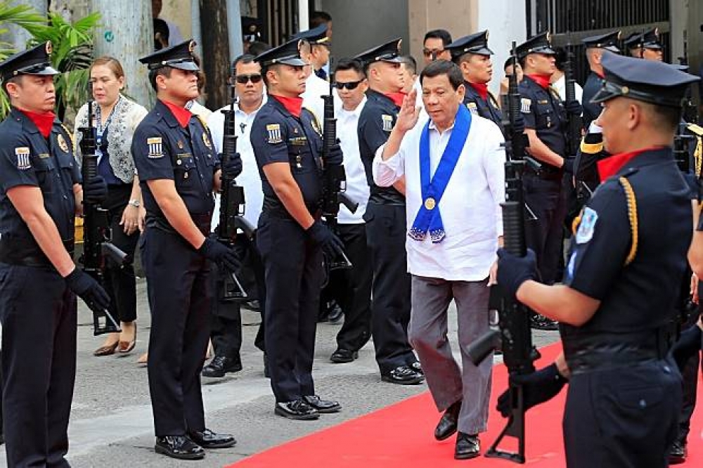 菲律賓總統杜特蒂經過菲律賓海關安全人員時舉手致意。（湯森路透）