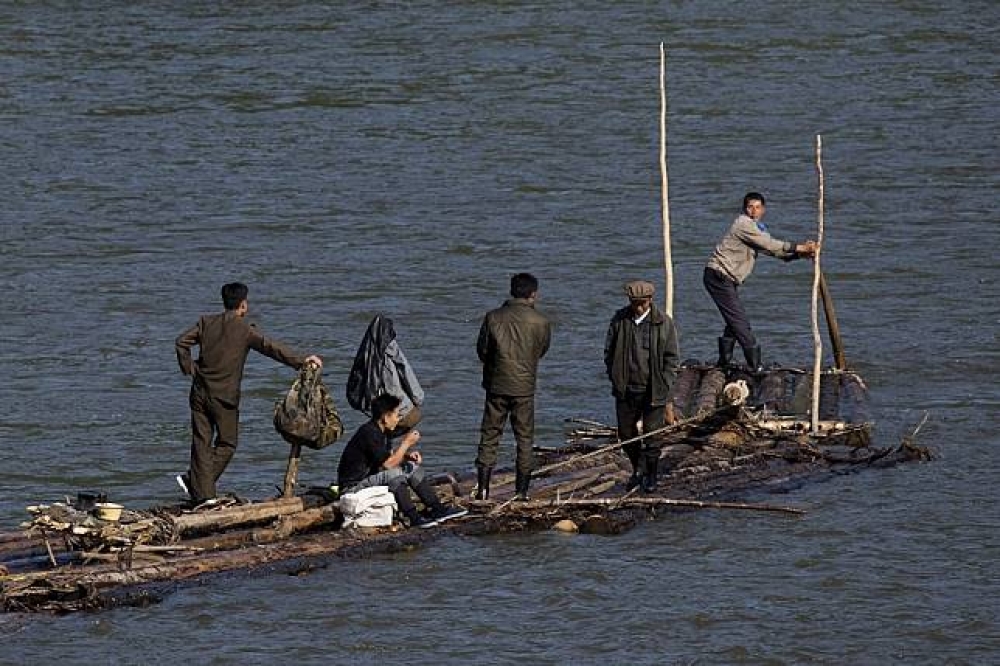 北韓人民划著自製木筏沿著中朝界河鴨綠江的下游過去。（美聯社）