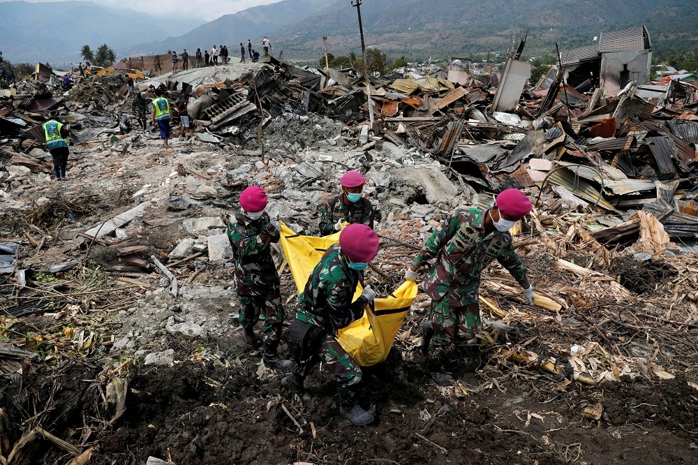 ４日印尼軍人從房屋瓦礫中搬運罹難遺體。（湯森路透）
