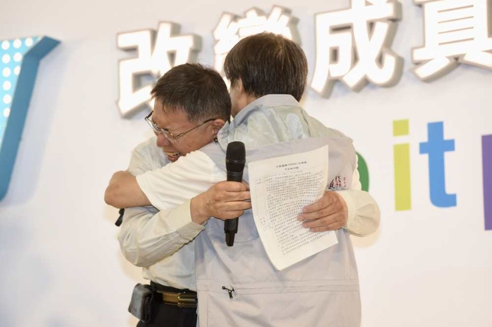 台北市長競選總幹事小野7日下午痛哭回應丁守中質疑，對此，柯文哲晚上出席競總活動時主動擁抱安慰小野，更向他致歉。（攝影：張文玠）