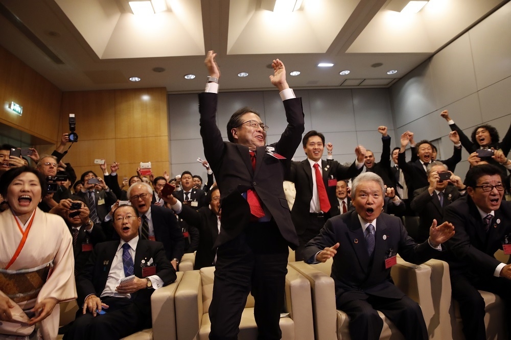 日本經濟產業大臣世耕弘成與代表團聽到大阪獲選2025年世博會主辦權，非常興奮、高舉雙手。（美聯社）