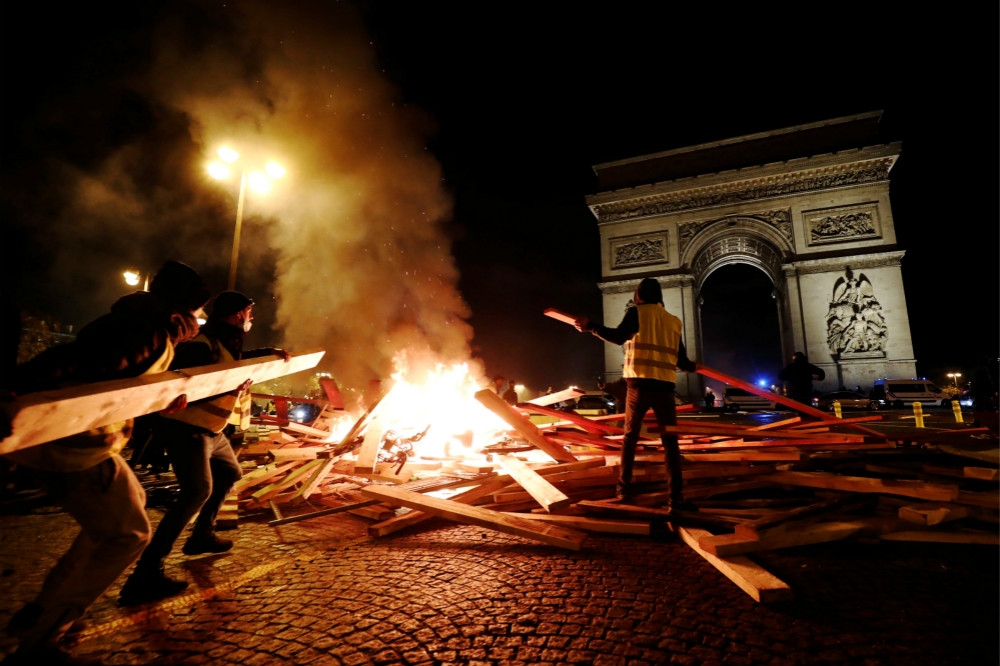 巴黎知名地標凱旋門前，抗議群眾焚燒物品表達抗議。（湯森路透）