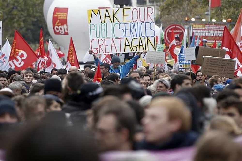 法國公務員走上巴黎市街頭。一人舉者「讓公共服務回到更好」牌子。（美聯社）