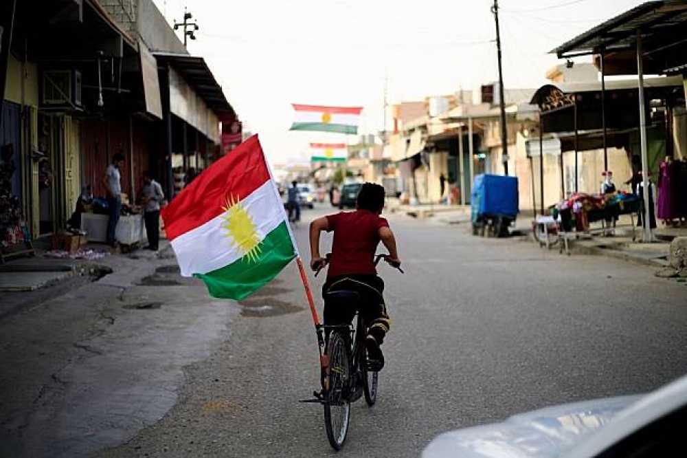 一名男孩的腳踏車後方掛著庫德族旗幟。（湯森路透）
