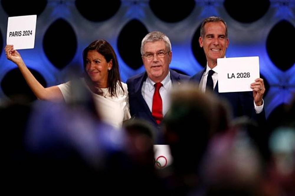 國際奧運會主席巴赫（中）分別握著洛杉磯市長賈西堤（右）及巴黎市長伊達戈（Anne Hidalgo）（左）。（湯森路透）