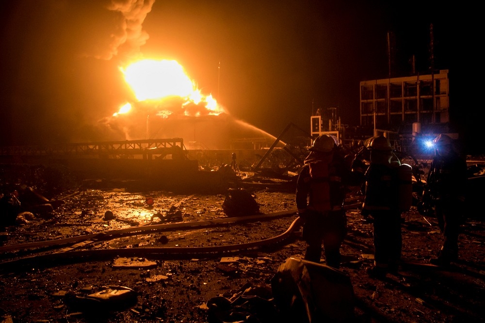 中國江蘇消防人員21日晚間拉水線撲滅火勢。（湯森路透）