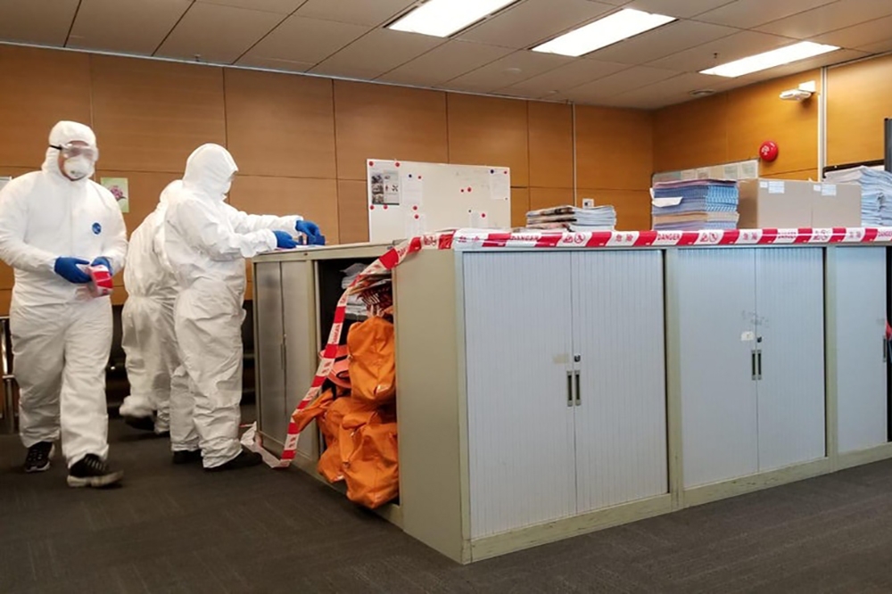 香港爆發小型爆麻疹疫潮，有穿上全套防護衣物人員在辦公室進行消毒。（資料圖片）