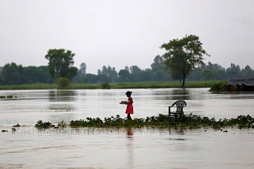 尼泊爾豪雨成災，一位女童站在淹水地區。（湯森路透）