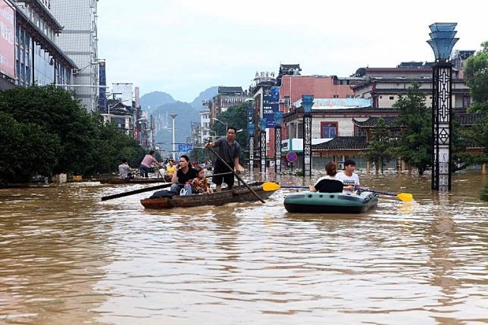 中國南方省分遭洪水淹沒，民眾坐上救生艇逃生。（湯森路透）