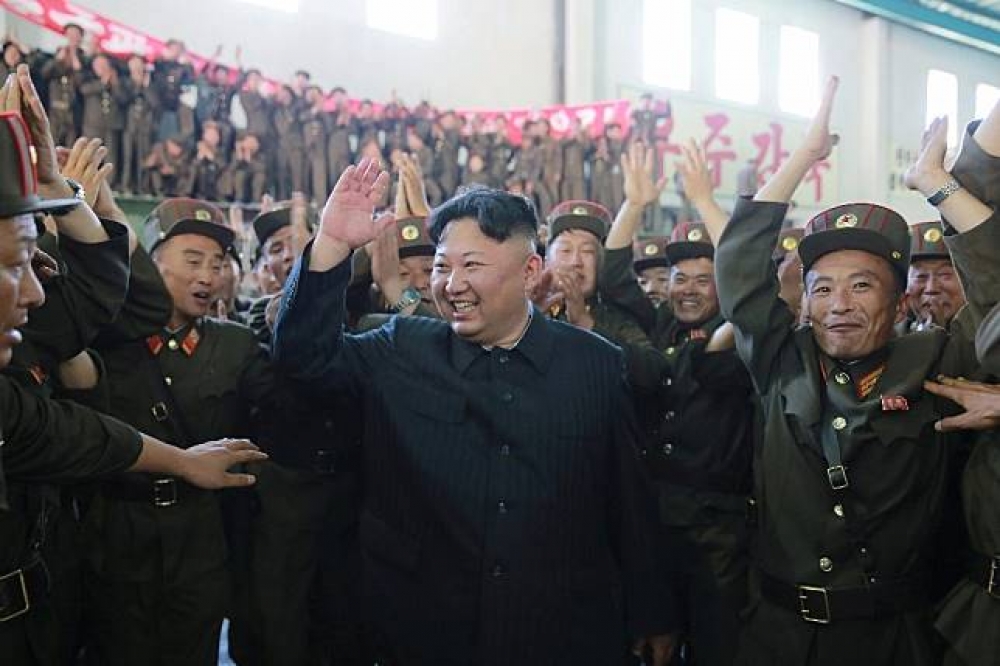 金正恩與北韓國防科學院研究人士開心慶祝試射成功。（湯森路透）