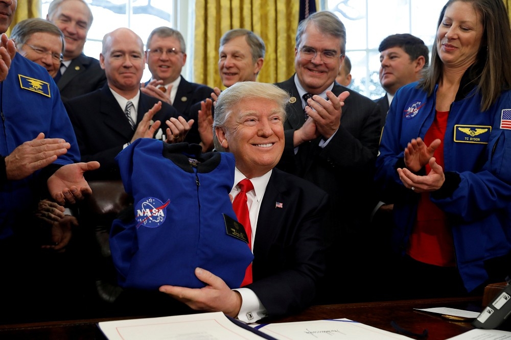 美國總統川普2017年3月21日在美國白宮簽署法案S.442，提供NASA195億美元資金，川普在儀式中獲得NASA的外套。（湯森路透）