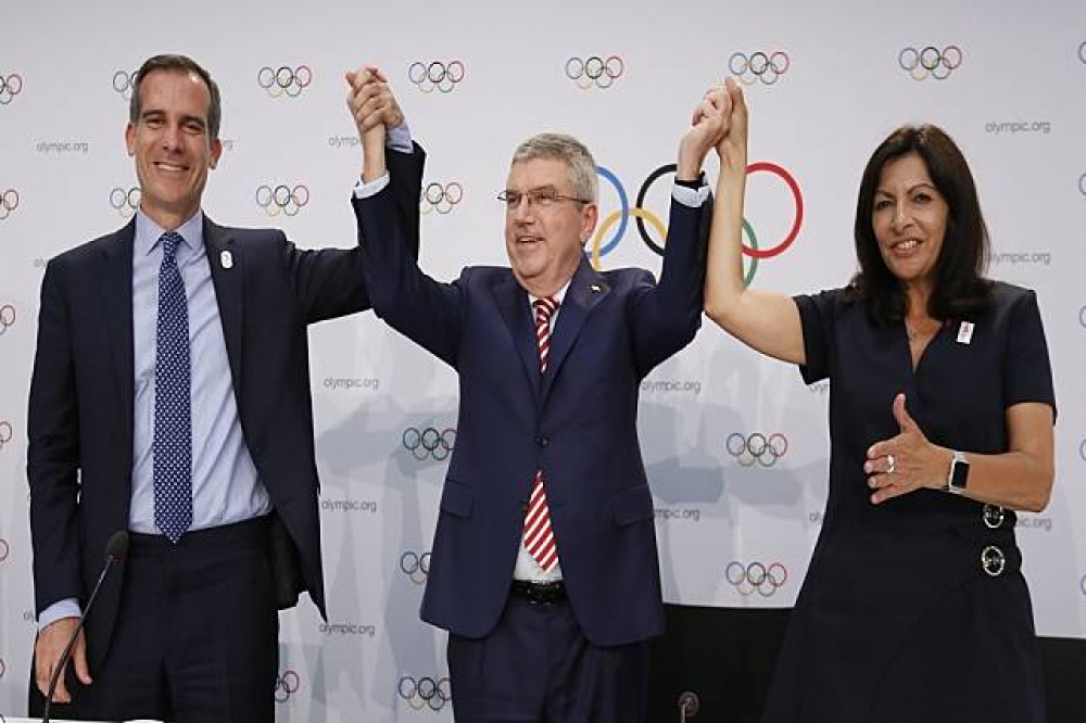 國際奧委會主席巴赫（中）分別握著洛杉磯市長賈西堤（左）及巴黎市長伊達戈（Anne Hidalgo）（右）。（湯森路透）