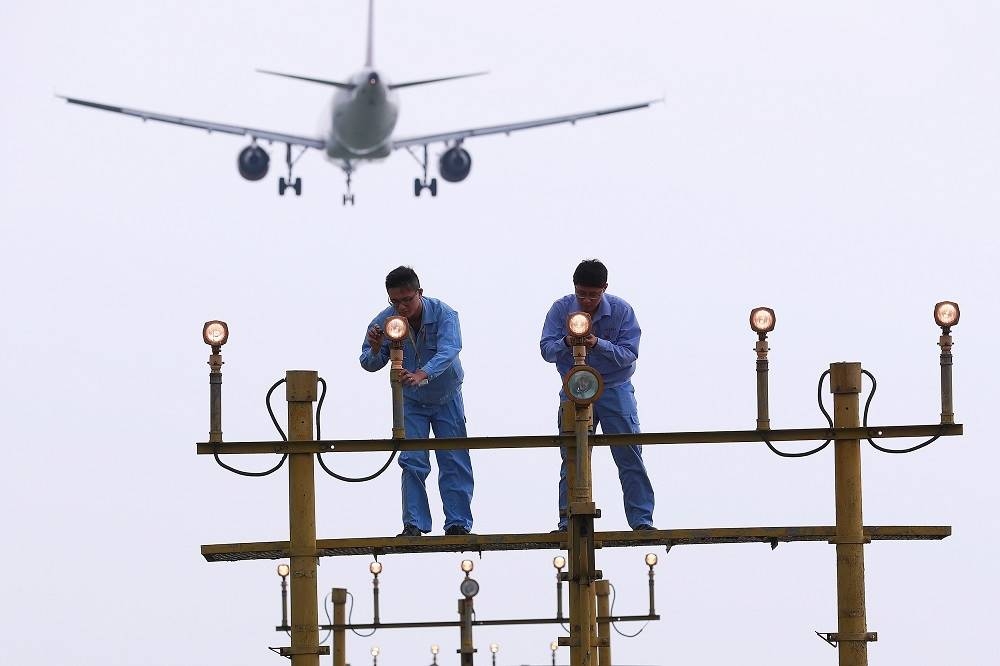 上海虹橋國際機場人員檢查維修照明系統。（湯森路透）