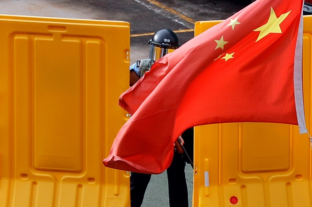 香港深水埗反送中抗議期間，中國國旗在防暴警察面前飄揚。（湯森路透）