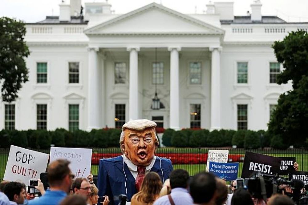 不滿美國總統川普兒子與俄國律師會面的抗議民眾11日於白宮前。（湯森路透）