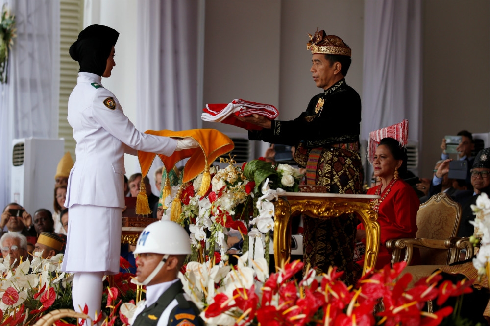 印尼總統佐科威（右）出席74年獨立日大典，向禮儀官遞交國旗。（湯森路透）