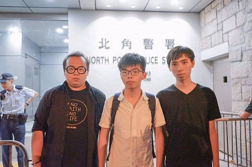 28日遭到港警拘留的香港眾志秘書長黃之鋒（中）30日凌晨終獲釋。（湯森路透）