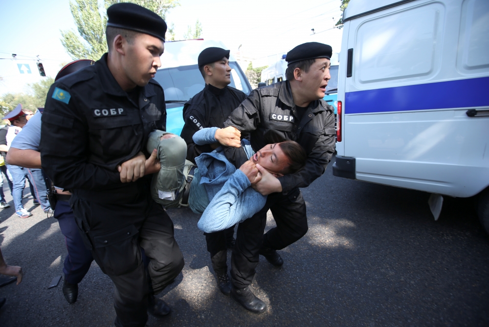 哈薩克第一大城阿拉木圖（Almaty）21日爆發反中國示威，抗議者遭警方強行拖上警車。（湯森路透）