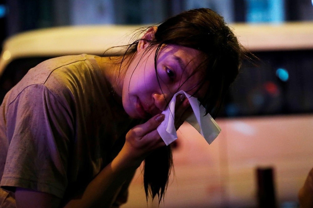 示威女子用紙巾擦拭受警方胡椒噴霧攻擊而不適的眼睛。（湯森路透）
