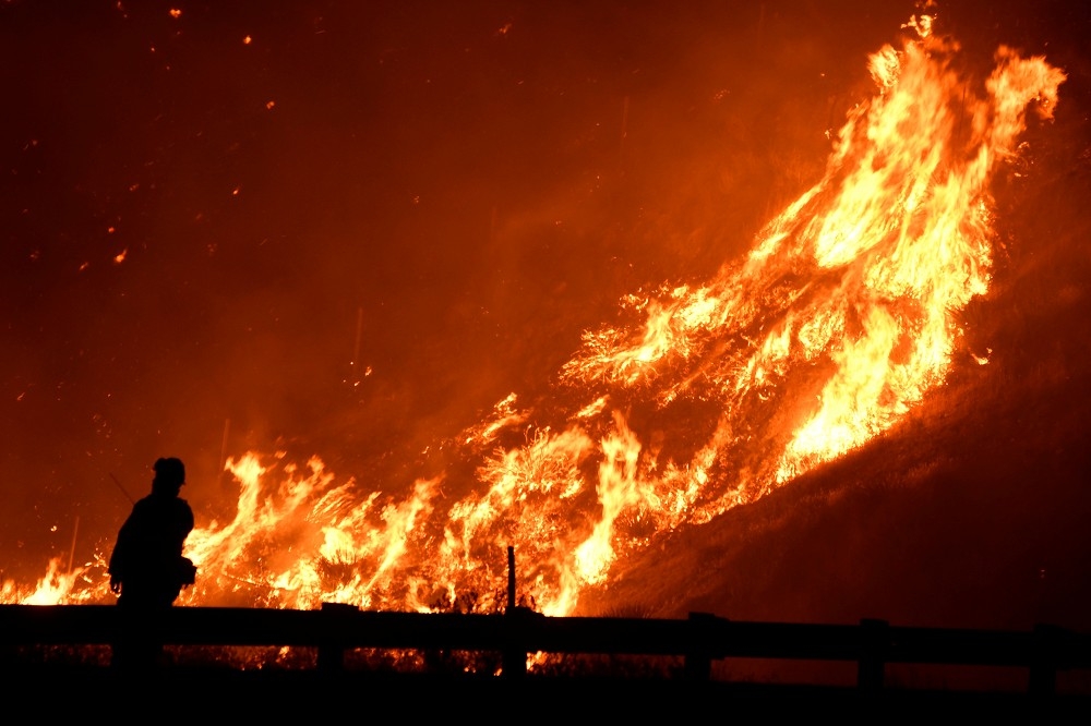 加州洛杉磯25日野火受強風吹拂，火勢持續。（湯森路透）