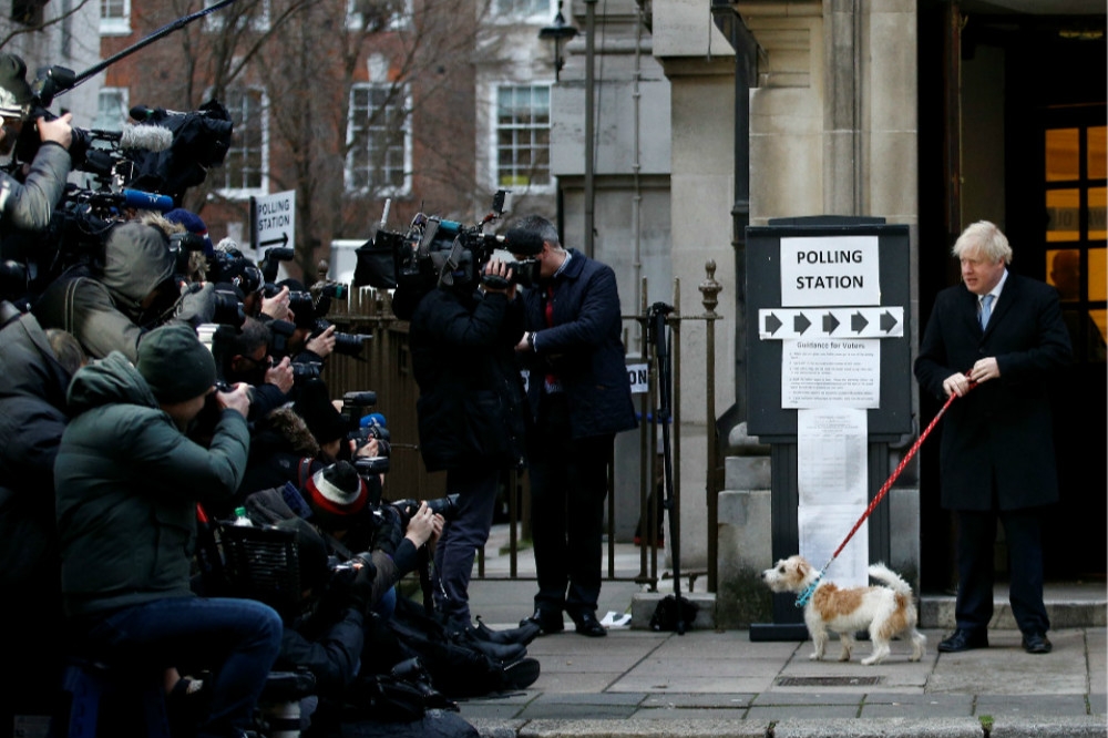 英國首相強森（右）牽著自己的寵物狗前往投票。（湯森路透）