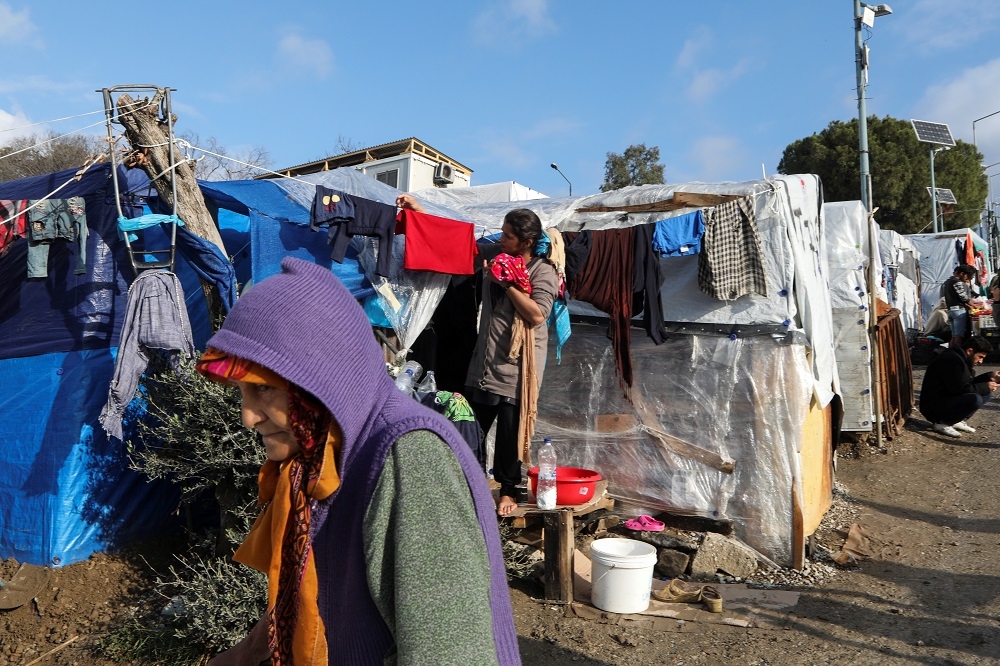 在希臘一處的難民營裡，一名女性正在收衣服。（湯森路透）