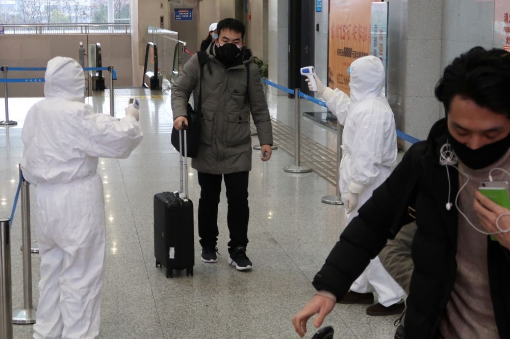 中國檢疫人員在車站為旅客量體溫。（湯森路透）