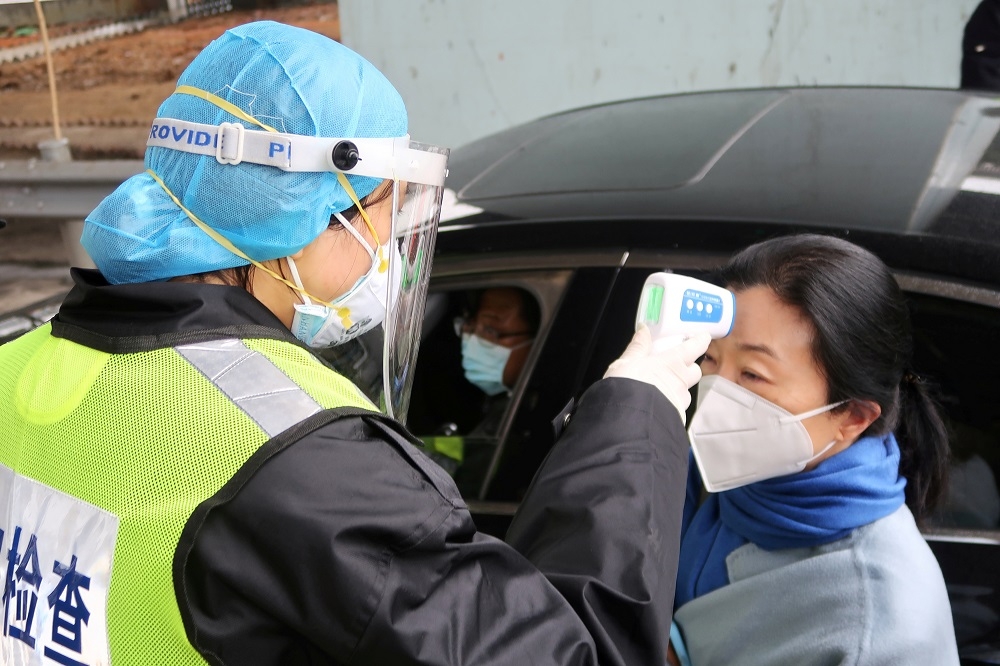 武漢肺炎防疫時期，湖北咸寧市社區出入人員皆須測量體溫。（湯森路透）