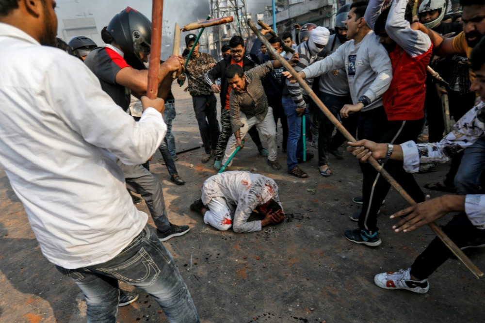 印度新德里24日爆發大規模抗爭，一群支持政府的民眾圍毆白衣穆斯林男子。（湯森路透）