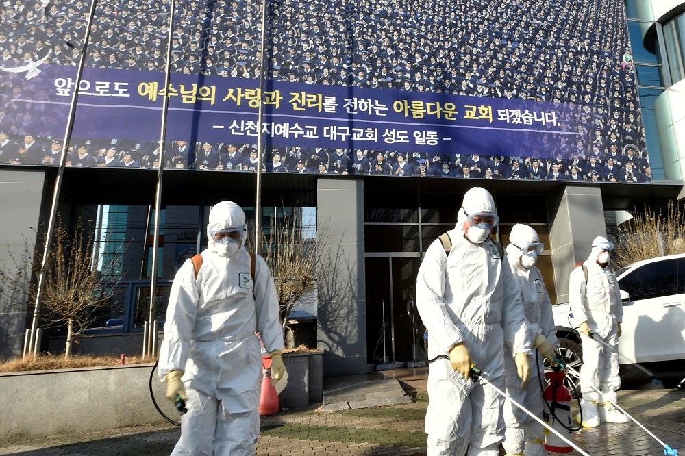 南韓大邱新天地耶穌教會外，衛生人員正進行消毒工作。（湯森路透）