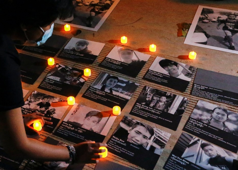 一名民眾在被軍事鎮壓中不幸喪生的死者照片旁放蠟燭。（湯森路透）