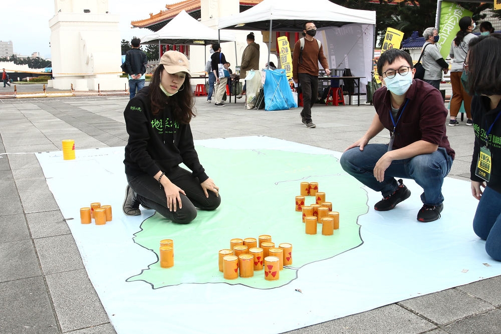 活動工作人員將代表核廢料的罐子，擺放在台灣地圖上。（王侑聖攝）