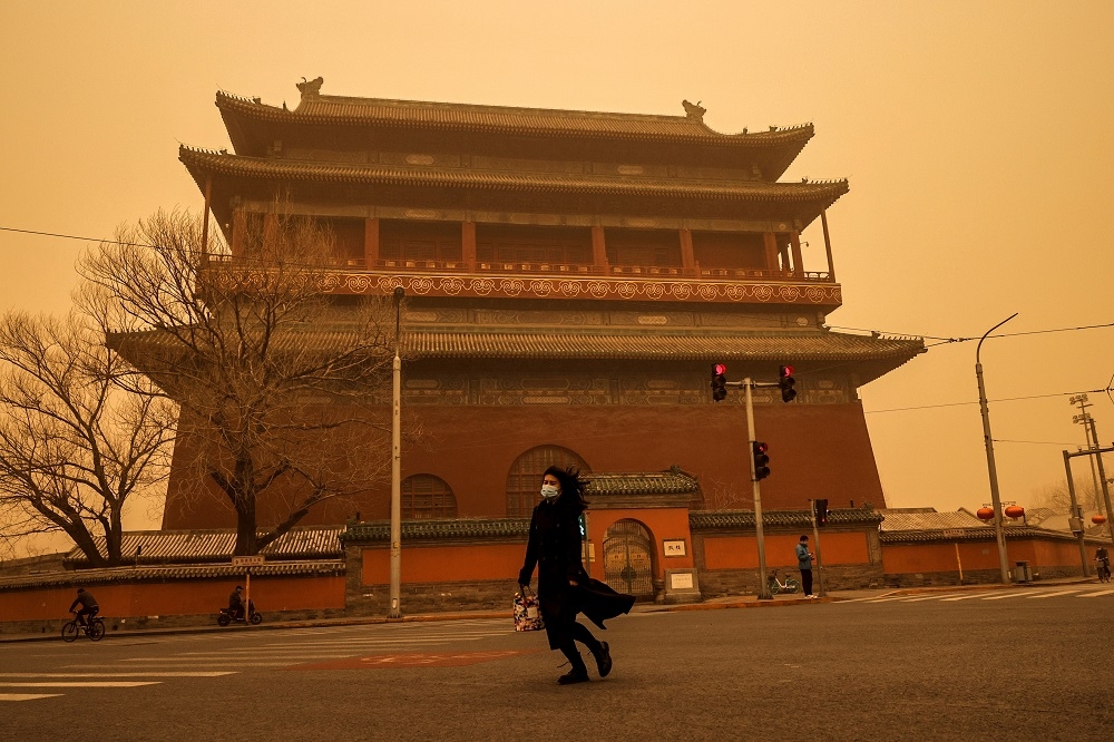 中國15日迎來近年最嚴重沙塵暴天氣，稍早上班時間，於北京鼓樓前一名女子過馬路景象。（湯森路透）