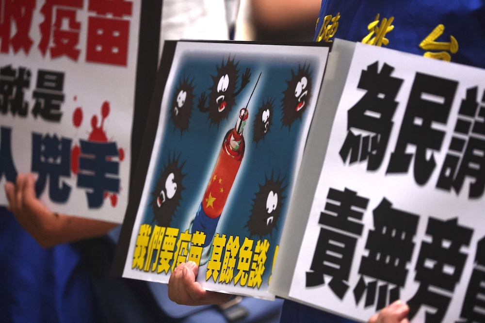 5月24日台灣疫情高峰時期，民眾在疫情指揮中心外舉牌要求政府接受中國疫苗。（湯森路透）