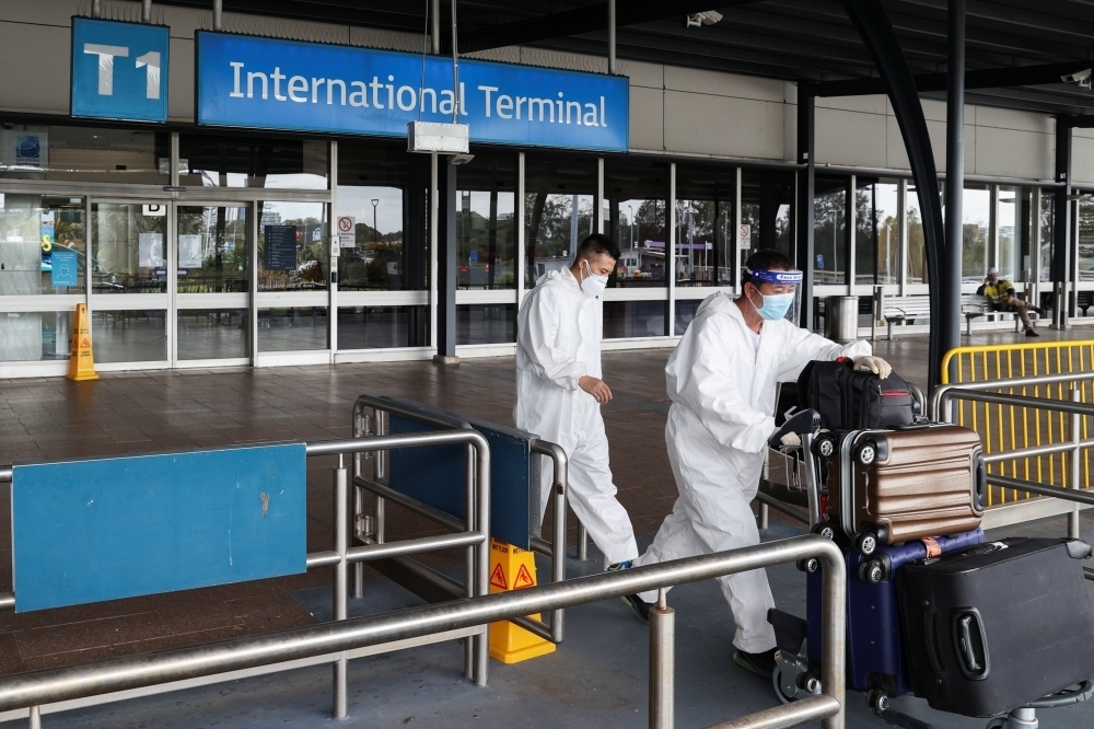 1名境外移入個案於10月底入境，12月確診時卻被列為境外移入，該案相關匡列者為國小學生，讓目前仍無接種疫苗的小學生，存在染疫風險。圖為在澳洲雪梨機場穿上防護衣的旅客。（湯森路透）