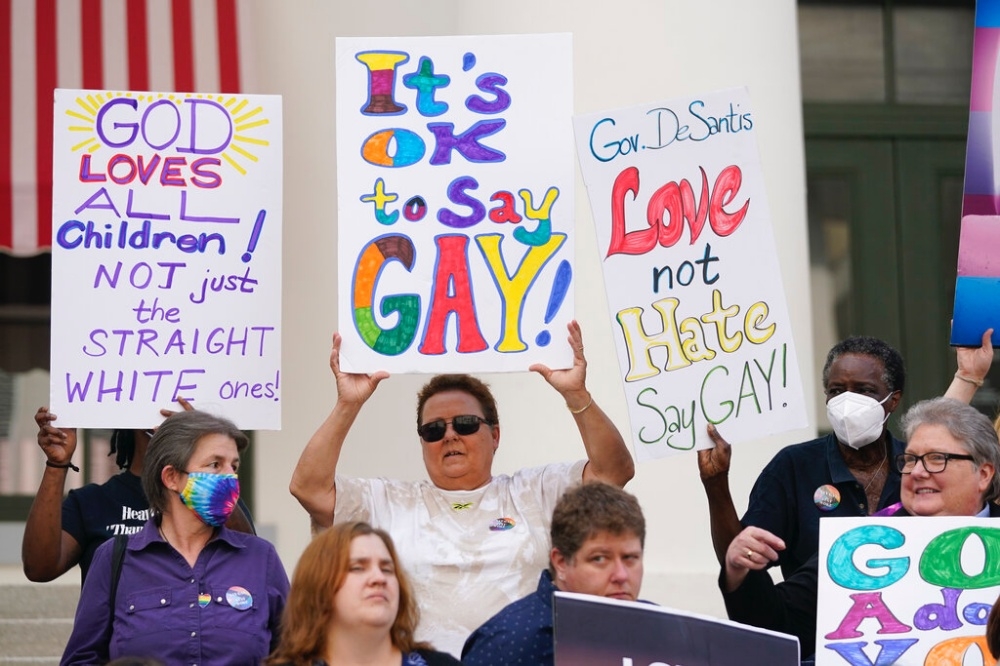 民眾聚集在佛羅拉達州議會大廈前，舉著「上帝愛所有的孩子，不是只有白人異性戀小孩」標語，抗議反同法案。（美聯社）